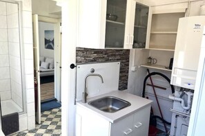 A compact kitchen with a built-in sink, white cabinets, and a stone backsplash. - Pension: Super apartment no. 2 in a prime location (Heide)