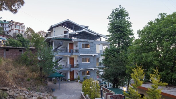 A multi-story building with a balcony, a staircase, and a pathway leading to the entrance. - Alaya Stays 1 BHK with Balcony & Breathtaking View | Baljees Melville Divine (Shimla)