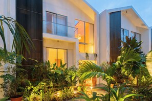 A modern house with a balcony, large windows, and a garden with various plants. - ELIVAAS Mirai Leo | 3 BHK Villa Near Vagator Beach With Pool (Vagator)
