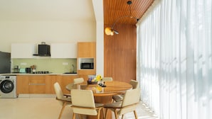 A modern kitchen with wooden cabinets, a built-in microwave, and a round dining table with chairs. - ELIVAAS Mirai Leo | 3 BHK Villa Near Vagator Beach With Pool (Vagator)