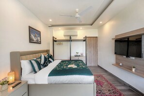 A modern bedroom with a bed, bedside table, nightstand, TV, and a ceiling fan.