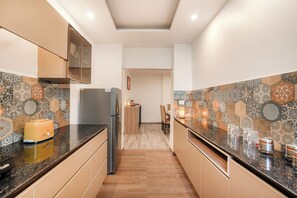 Lemari es, microwave, peralatan masak/sendok-piring, dan meja makan