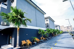 A hotel corridor with palm trees, benches, and a clear sky. - Atlantis Hotels & Apartment (Port Harcourt)