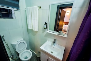 A bathroom with two toilets, a sink, a mirror, and a shower curtain. - Atlantis Hotels & Apartment (Port Harcourt)