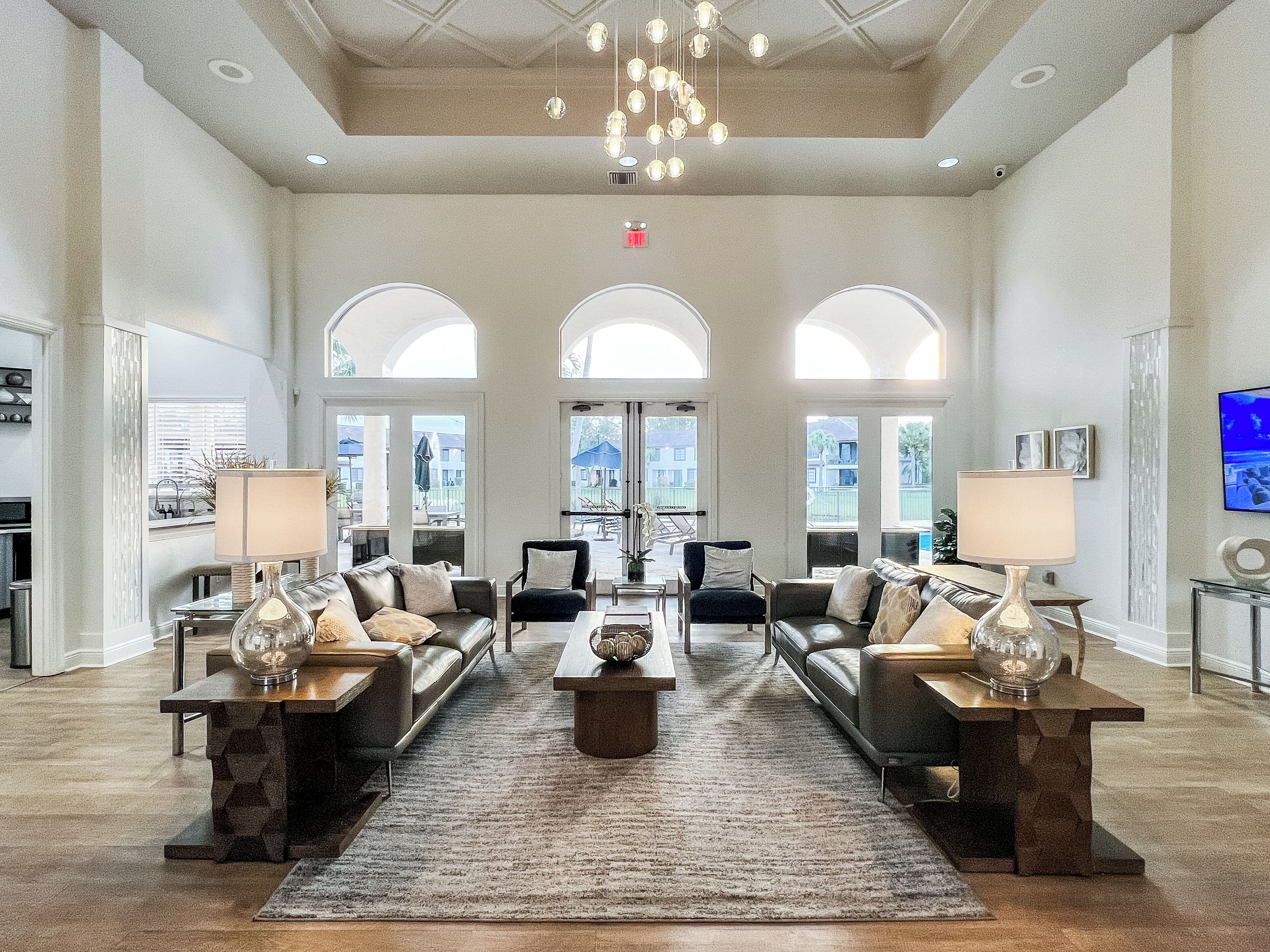 A spacious lobby with a high ceiling, large windows, and a central seating area with sofas and tables.