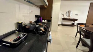 A modern kitchen with a gas stove, pots, and a coffee machine. - LUMAANA RESIDENCES (Abuja)