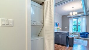 A laundry room with a washing machine and dryer, a small kitchenette with a sink and cabinets, and a dining area with a chair and table. - Chicago Spacious 3Br Smoke Ok Near McCormick Place (Chicago)