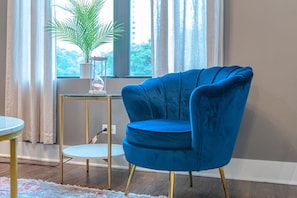A blue armchair with gold legs, a small round table, and a potted plant on a glass table beside a window with curtains. - Chicago Spacious 3Br Smoke Ok Near McCormick Place (Chicago)