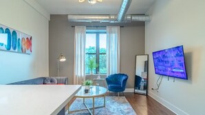 A modern living room with a sofa, a round coffee table, a blue armchair, a TV, and a large window with curtains. - Chicago Spacious 3Br Smoke Ok Near McCormick Place (Chicago)