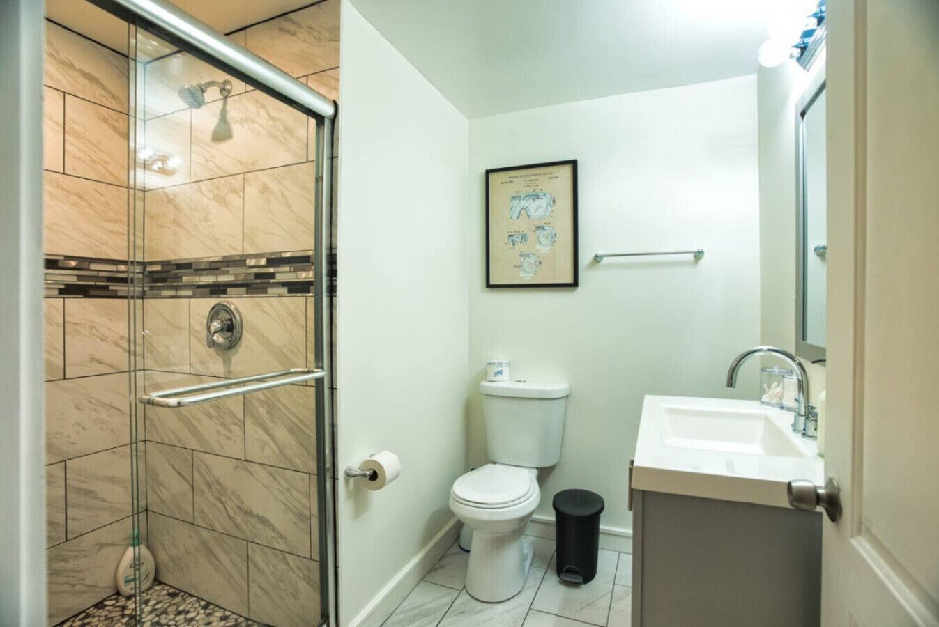 Une salle de bain avec une douche à parois de verre, des toilettes, un lavabo et un tableau encadré au mur.