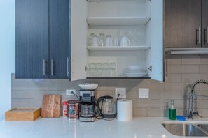 A kitchen with a coffee maker, a kettle, and a toaster on the counter. - Stylish friendly 3BR Suite near McCormick (Chicago)