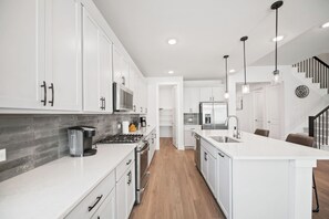 A modern kitchen with white cabinetry, stainless steel appliances, and a wooden floor. - MCK716 - Home|Yard|16mi to Toyota Stadium|Sleeps 8 (Mckinney)