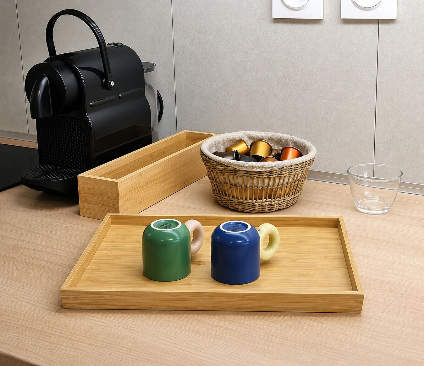 A kitchen counter with a coffee maker, a basket of mugs, and a tray with two mugs.