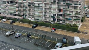 Un edificio residencial de varios pisos con balcones y un estacionamiento al frente.