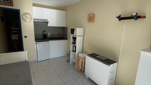 Una cocina compacta con armarios blancos, un microondas y un lavamanos.