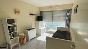 Un espacio habitable compacto con kitchenette, un pequeño comedor y vistas a través de una puerta corredera.