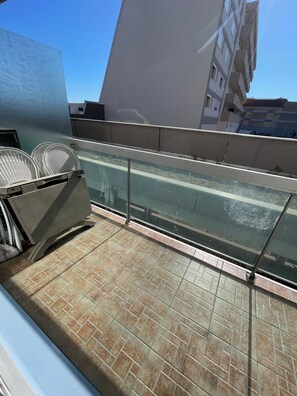 Un balcon doté d’une paroi en verre, d’une rambarde en métal et d’un sol carrelé.