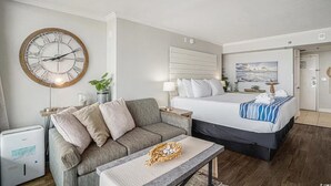 A hotel room with a bed, a sofa, a small table, a wall clock, and a painting. - Cozy condo in wonderful Myrtle Beach with refreshing AC (Myrtle Beach)