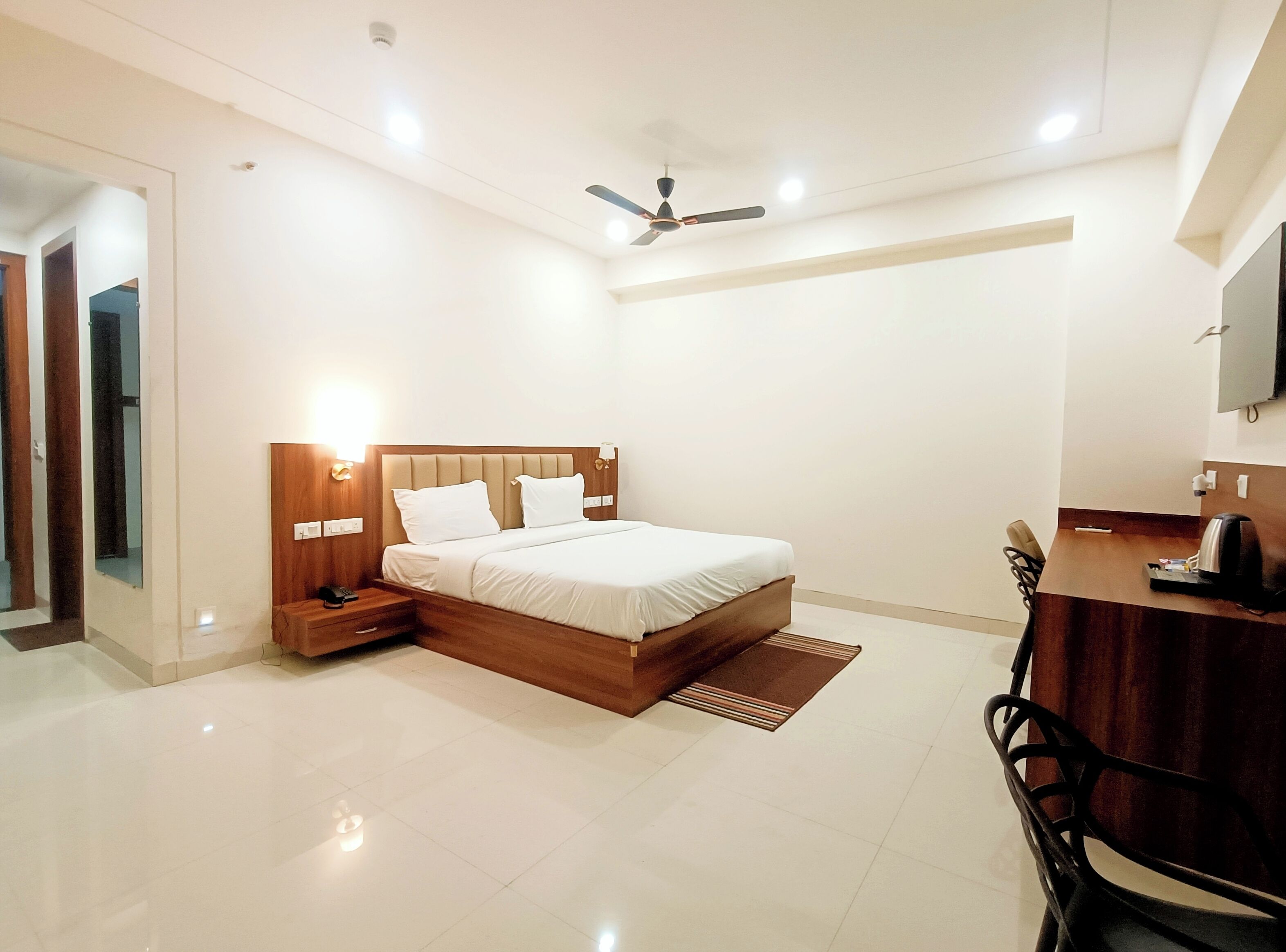 Una habitación de hotel moderna con una cama grande, mesitas de noche, un escritorio y una silla.