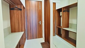A walk-in closet with wooden doors, shelves, and a hanging rod. - Hotel Krishna Anandam Regency (Vrindavan)