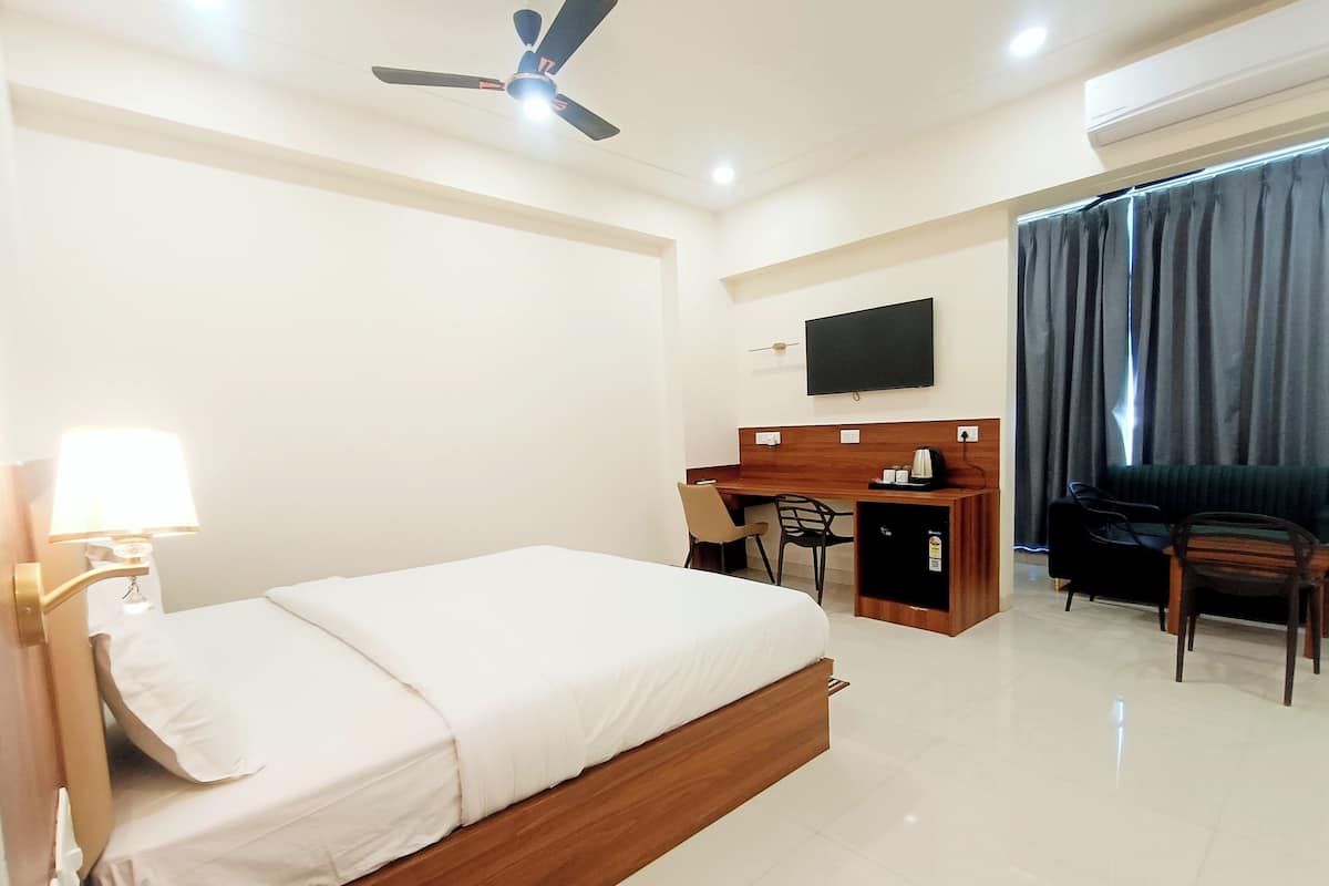 Une chambre d’hôtel avec un lit, un bureau, une chaise et un téléviseur fixé au mur.