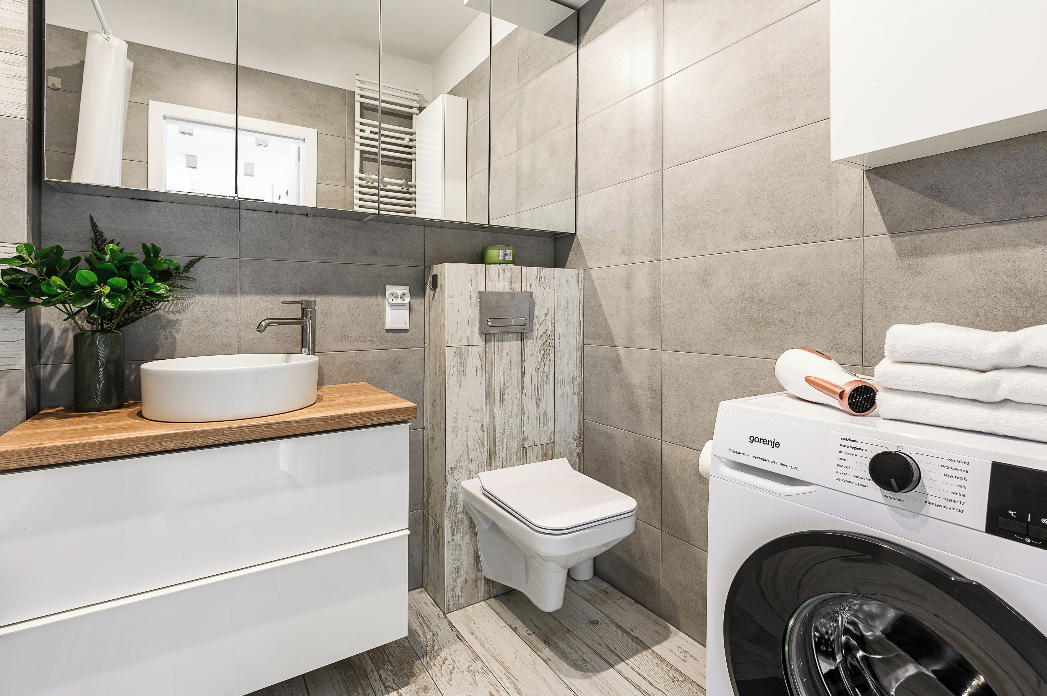 Een moderne badkamer met een wastafel, toilet en een ingebouwde wasmachine.