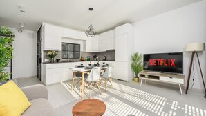 A modern living room with a sofa, coffee table, and a TV displaying 'NETFLIX'. - Lumina Family apartment with patio (Warsaw)