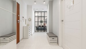 A hallway with a wooden door, a white cabinet, and a bench. - Lumina Family apartment with patio (Warsaw)