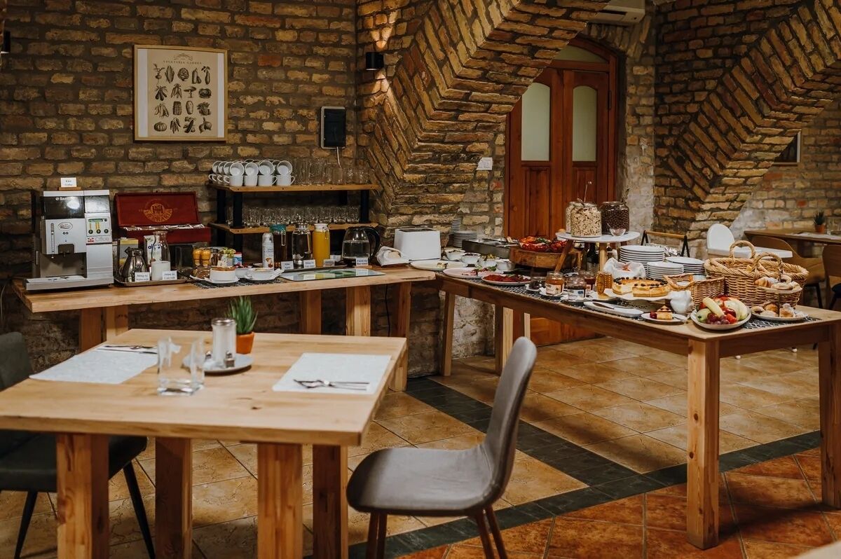 A restaurant with a brick wall, wooden tables, and a variety of food and drink items.