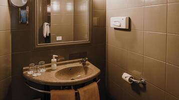 Une salle de bain équipée d’un lavabo, d’un miroir, d’un porte-serviettes et d’un sèche-mains.