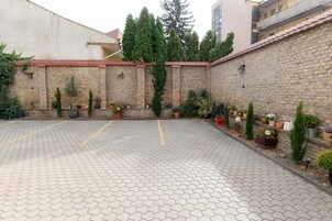 A courtyard with a paved floor, brick walls, and potted plants.