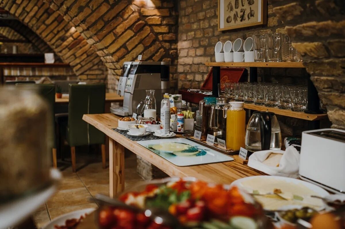 A breakfast buffet setup with various food items and beverages, a coffee machine, and a brick wall background.