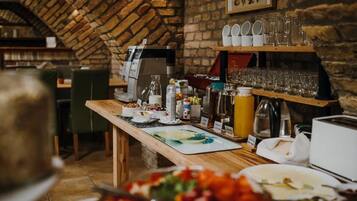 A breakfast buffet setup with various food items and beverages, a coffee machine, and a brick wall background.