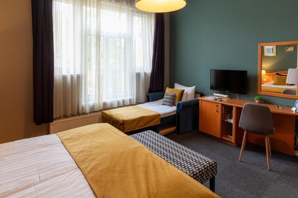 Een hotelkamer met twee bedden, een bureau, een televisie en een spiegel.