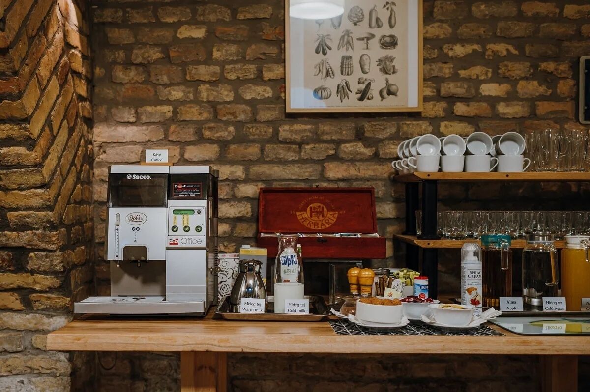 A coffee station with a Saccocino machine, a coffee grinder, and a variety of coffee beans and milk options.