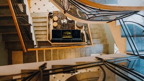 Una escalera moderna con diseño curvo, barandilla de madera y una zona de estar acolchada en color negro al final.