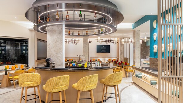 A modern bar area with a circular bar, multiple stools, and a variety of bottles displayed on the bar top. - Hotel Gwalior Regency, a member of Radisson Individuals (Gwalior)