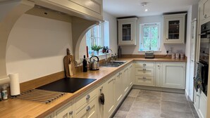 Una cocina moderna con encimera de madera, electrodomésticos de acero inoxidable y armarios blancos.