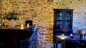 A stone-walled bar area with a wooden cabinet, bar stools, and a tiled floor. - Luxury suite in charming B&B in Galicia (O Agro)