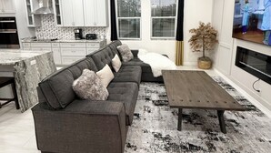 A modern living room with a sectional sofa, a coffee table, and a TV. - Brand New Luxury Modern 5BR/4.5BA+Game Room Home (Altamonte Springs)