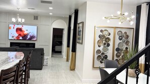 A modern kitchen with a dining area, a TV, and a staircase. - Brand New Luxury Modern 5BR/4.5BA+Game Room Home (Altamonte Springs)