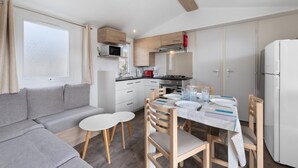 Una cocina compacta con armarios blancos, un microondas, una cocina a gas y un refrigerador.