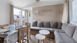 Una sala de estar moderna con un sofá, una mesa de comedor, sillas y una pequeña mesa blanca.