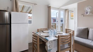 Cocina compacta con una mesa de comedor para cuatro, refrigerador y un sofá en la sala de estar contigua.