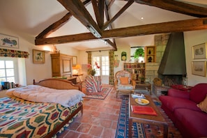 A cozy room with a bed, a red sofa, a wooden coffee table, and a fireplace. - A Chateau for all generations. (Saint-Victor-Rouzaud)