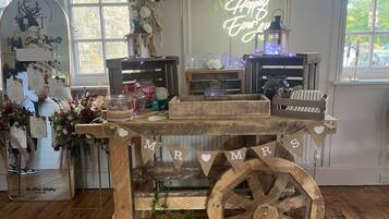 A rustic wedding setup with a wooden cart labeled "MR & MRS" and a neon sign saying "Happily Ever After".
