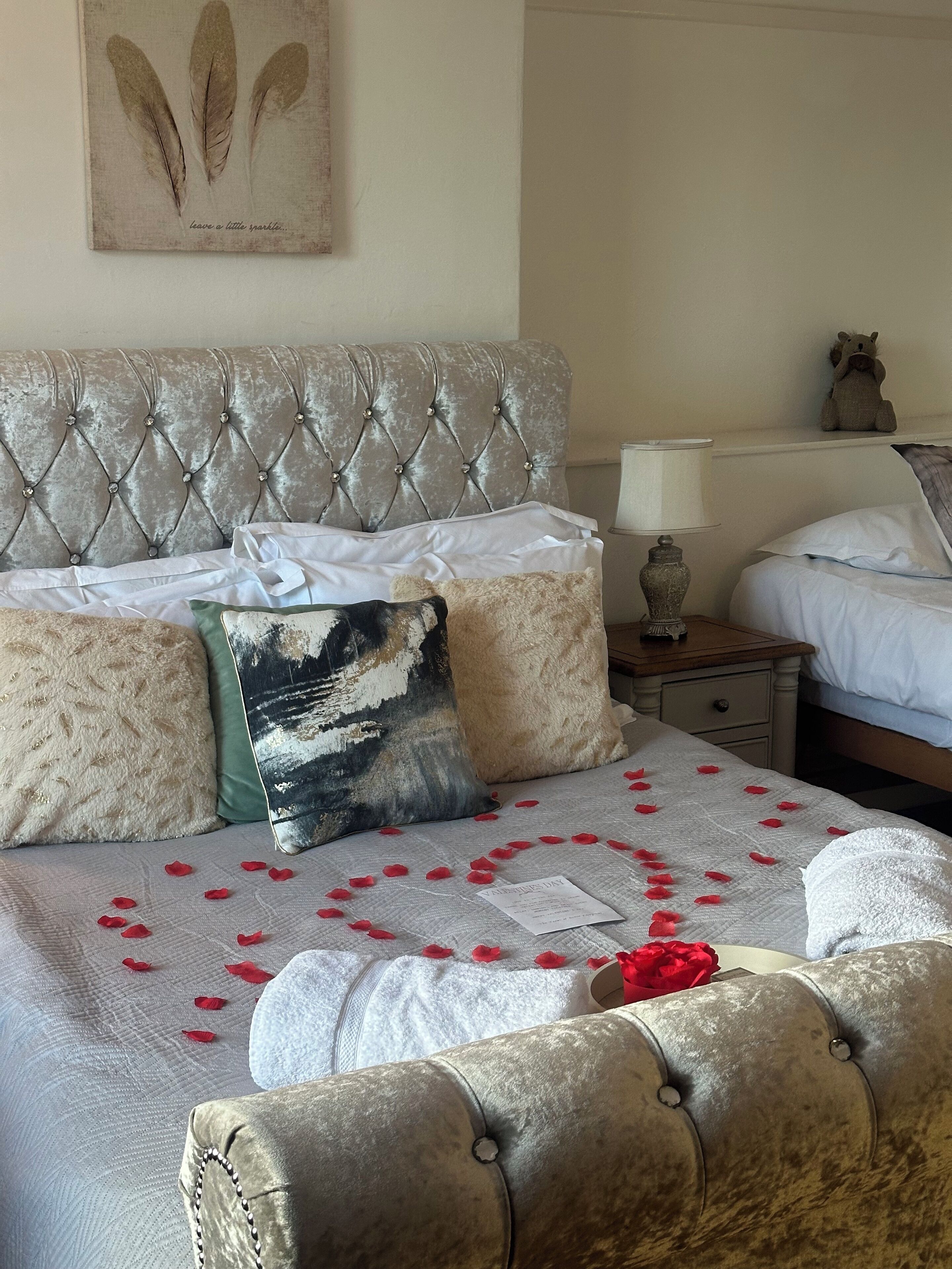 A neatly made bed with a tufted headboard, multiple pillows, and a decorative pillow with a nature scene.