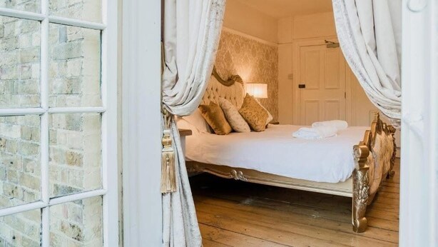 Een slaapkamer met een bed, gordijnen en een bakstenen muur.