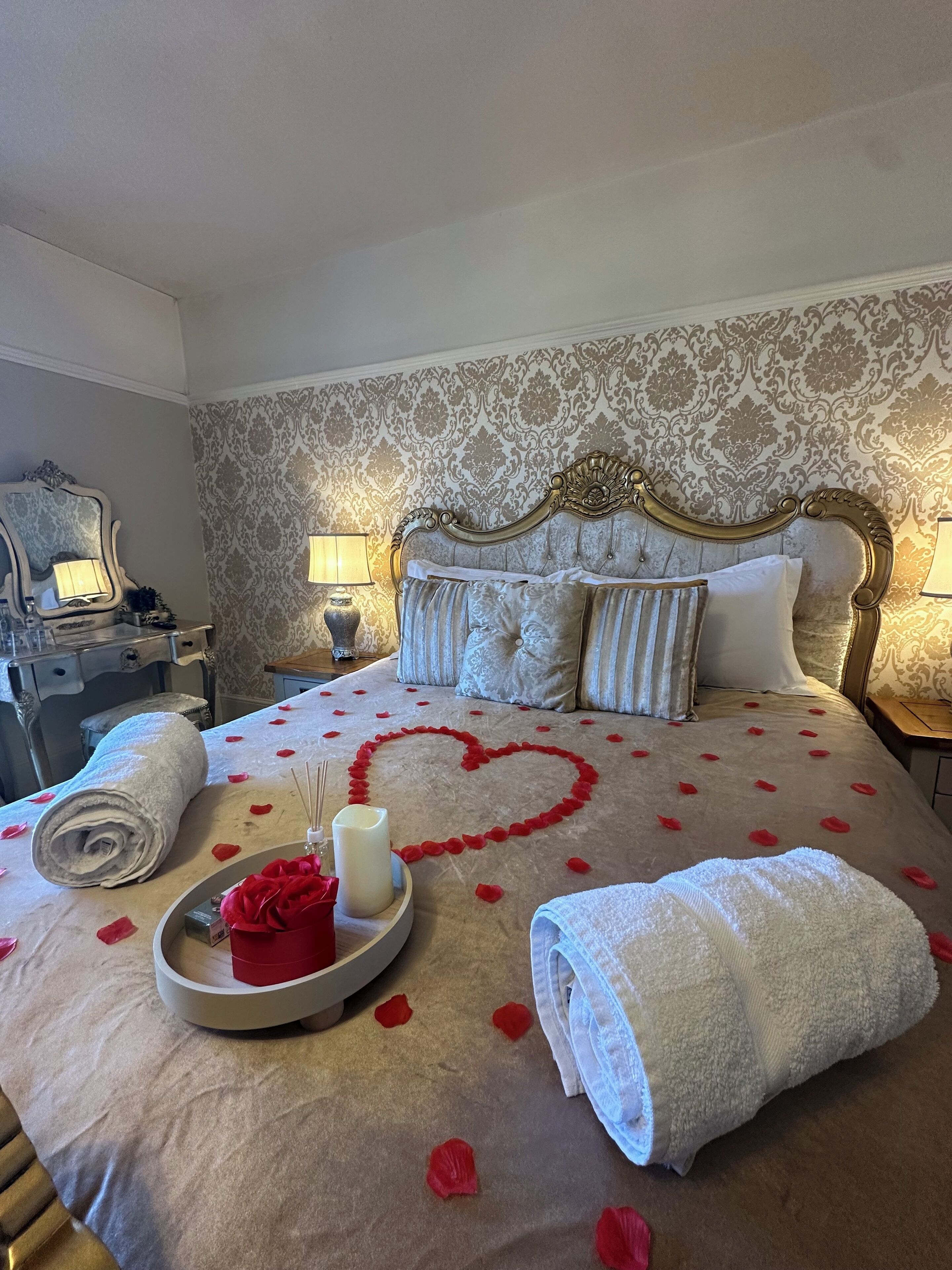Quarto de hotel com uma cama grande, cabeceira elaborada e um detalhe decorativo na parede.