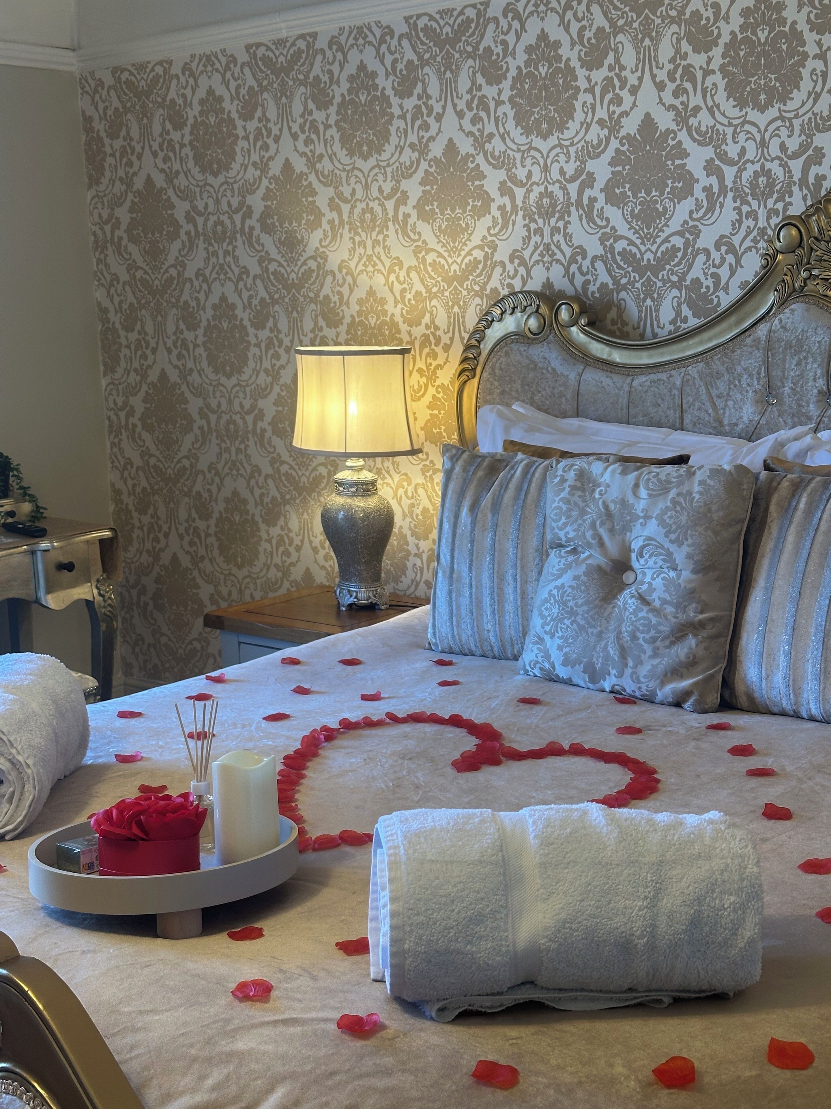A hotel room with a bed, a nightstand, a lamp, and a decorative wall.